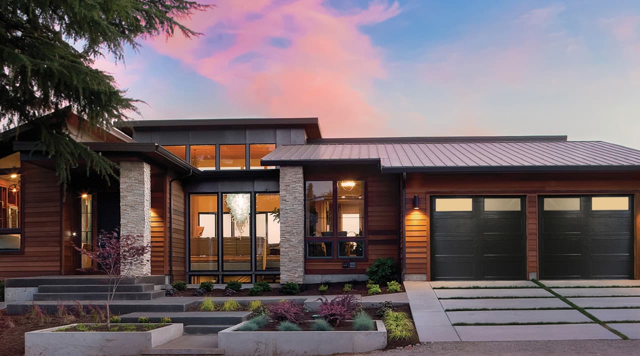 Modern Alberta home with insulated black garage doors at dusk